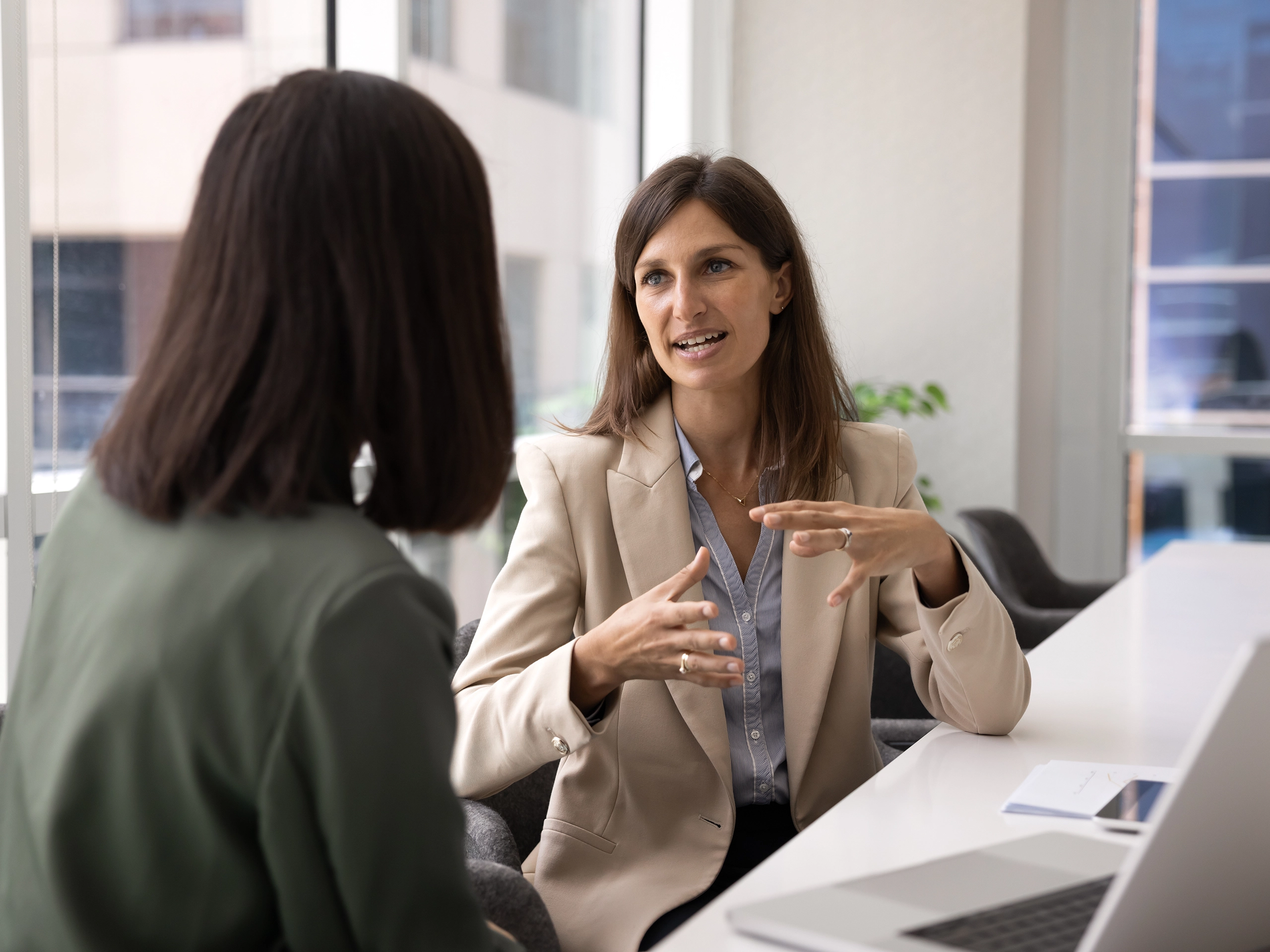 Young Caucasian business company executive woman talking to professional expert, consultant, advisor, discussing online product with partner, female coworker at meeting table