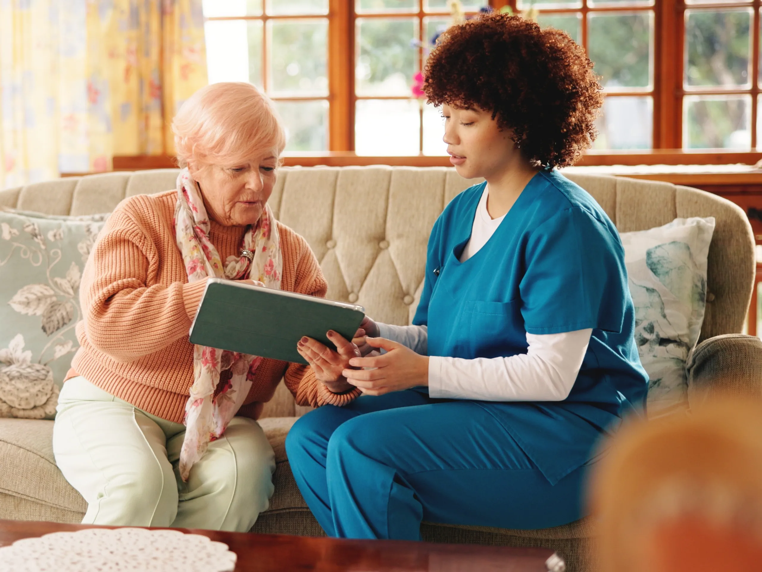 Femal domiciliary carer with her client, sat on a sofa