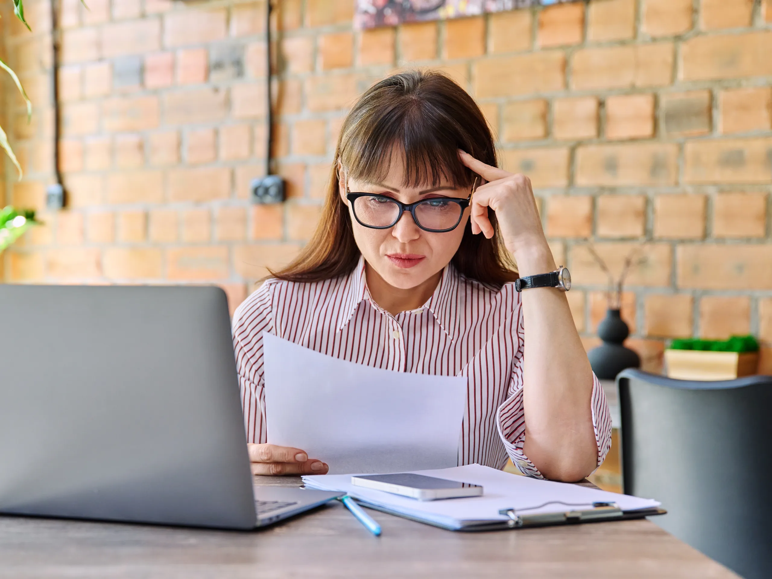 Employee pay concerns_woman concerned, thinking, holding paperwork