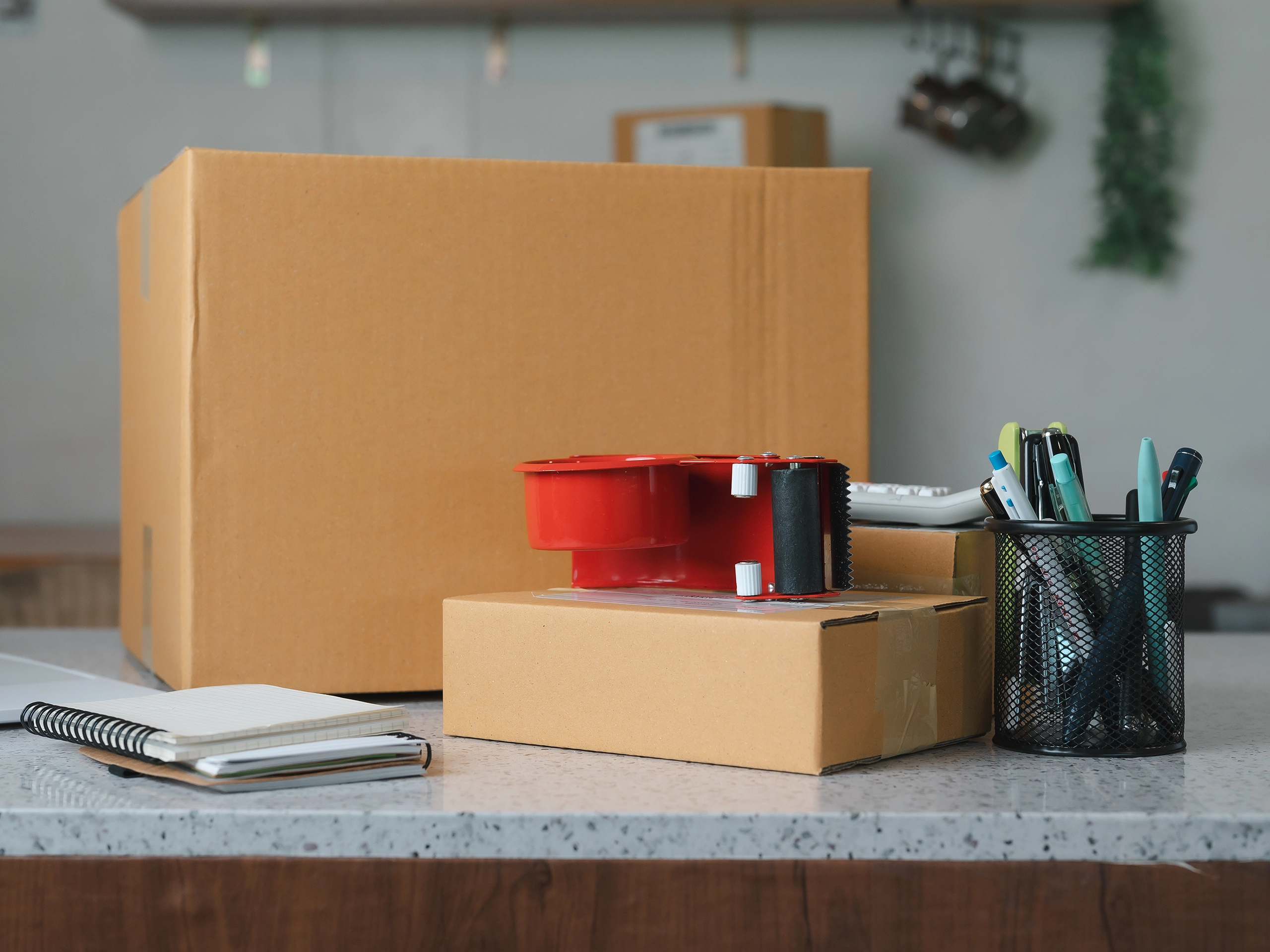 Entrepreneur home office workspace featuring cardboard parcel boxes laptop and packing supplies during e-commerce business shipping operations
