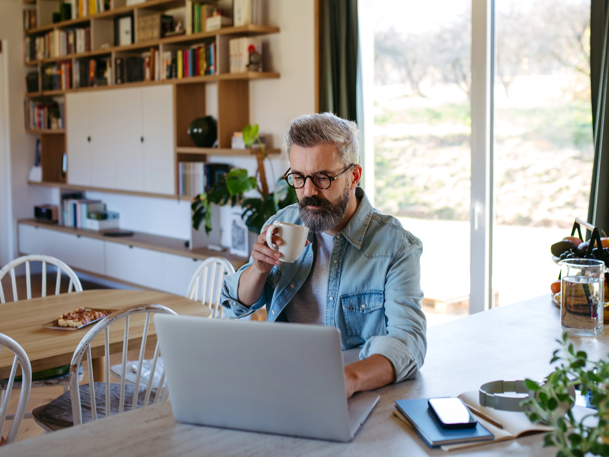 Man working from home office, drinking coffe and working on laptop.