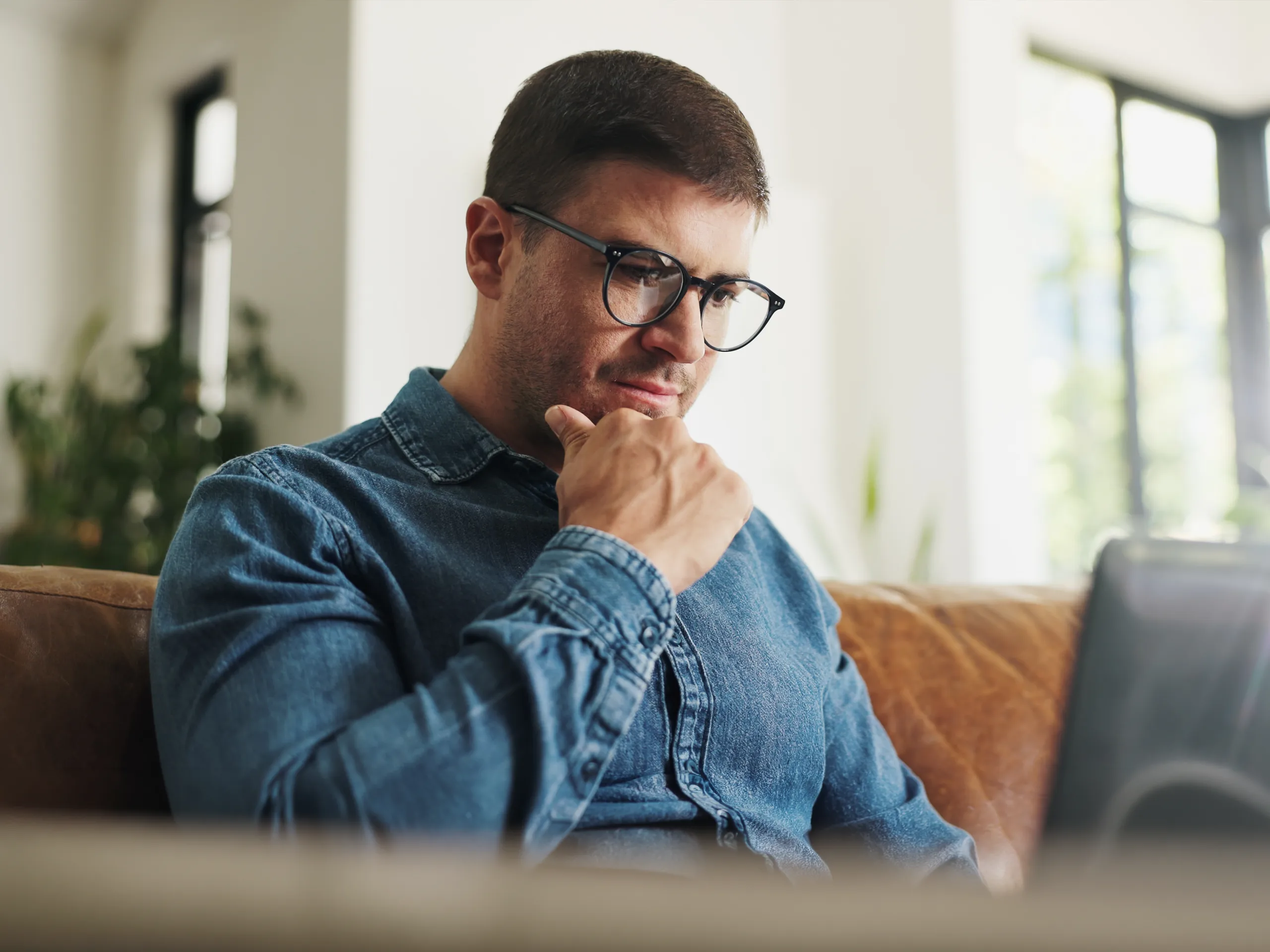 Business man sat on his sofa looking at laptop