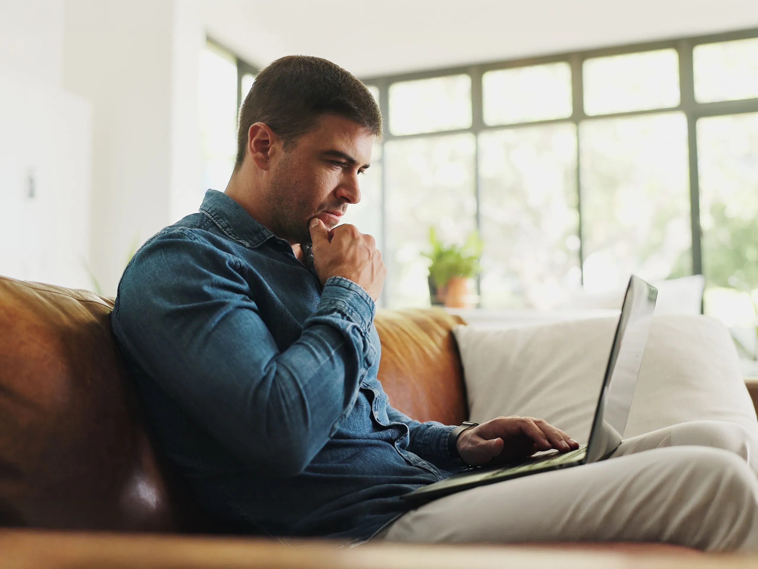 Business man sat on the sofa checking his chances of success on laptop