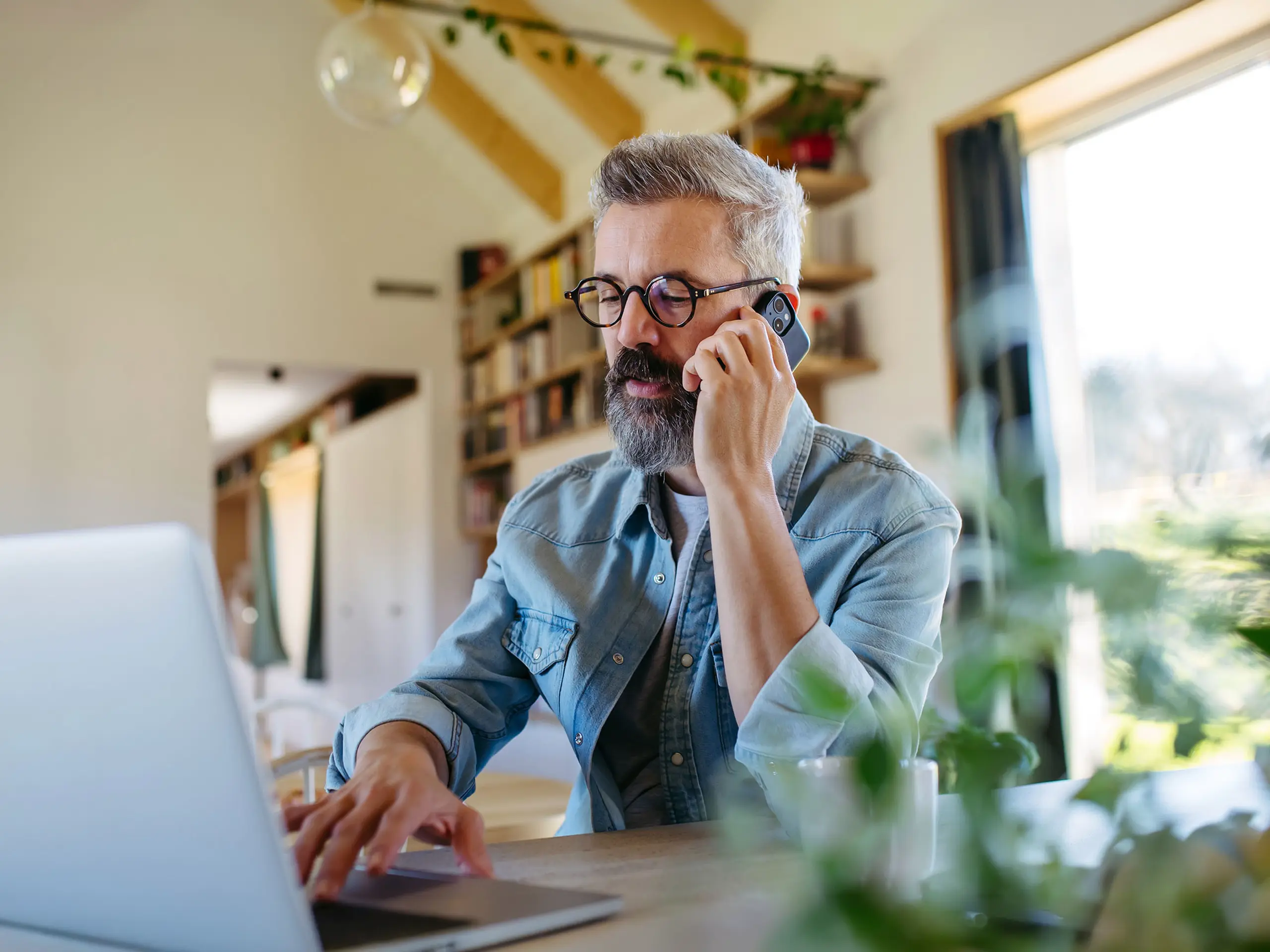 business man working from home with laptop, talking at the phone