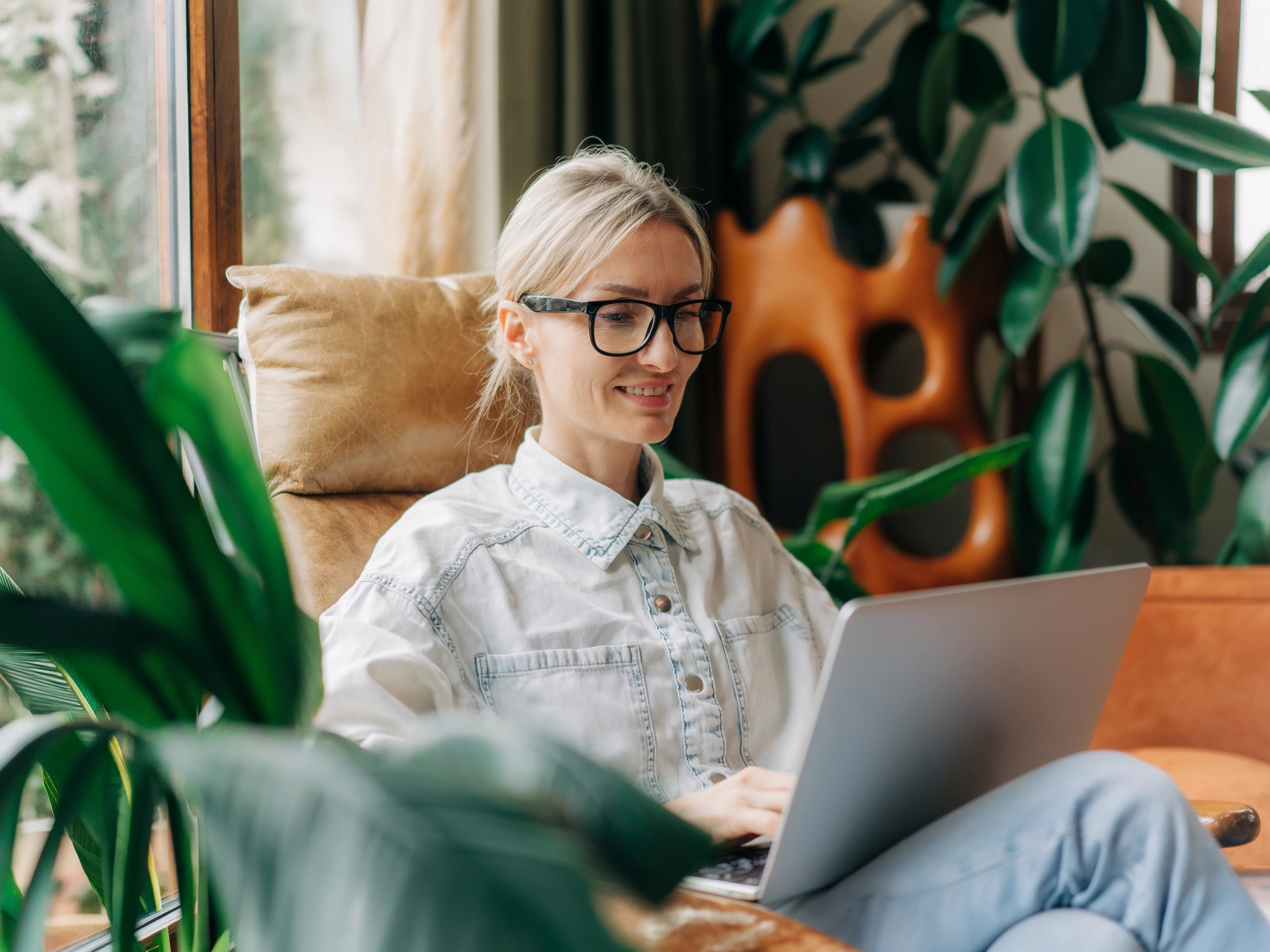 Happy smiling businesswoman working at her laptop sat on a armchair