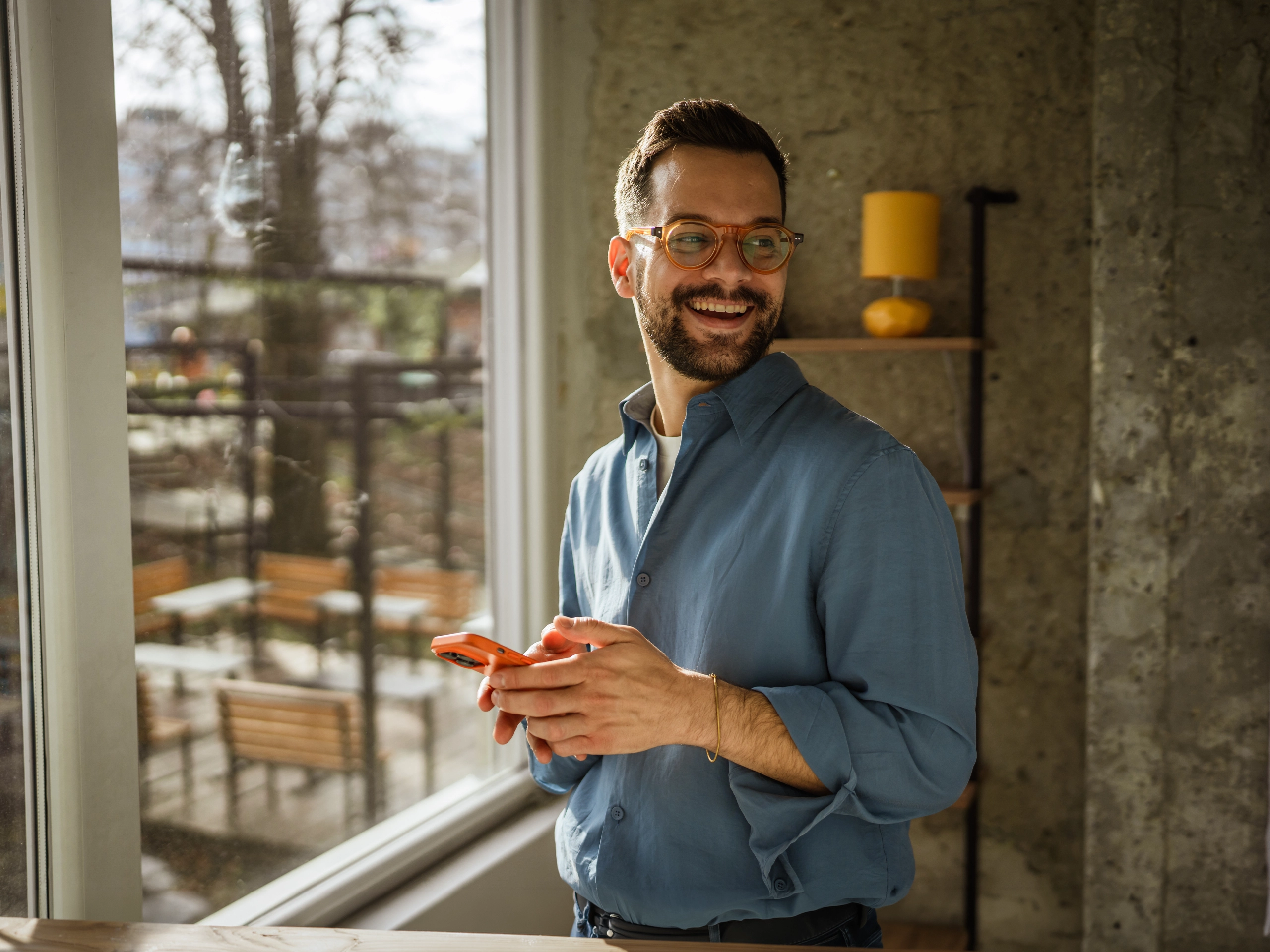 Business man holding his phone, smiling and looking relaxed