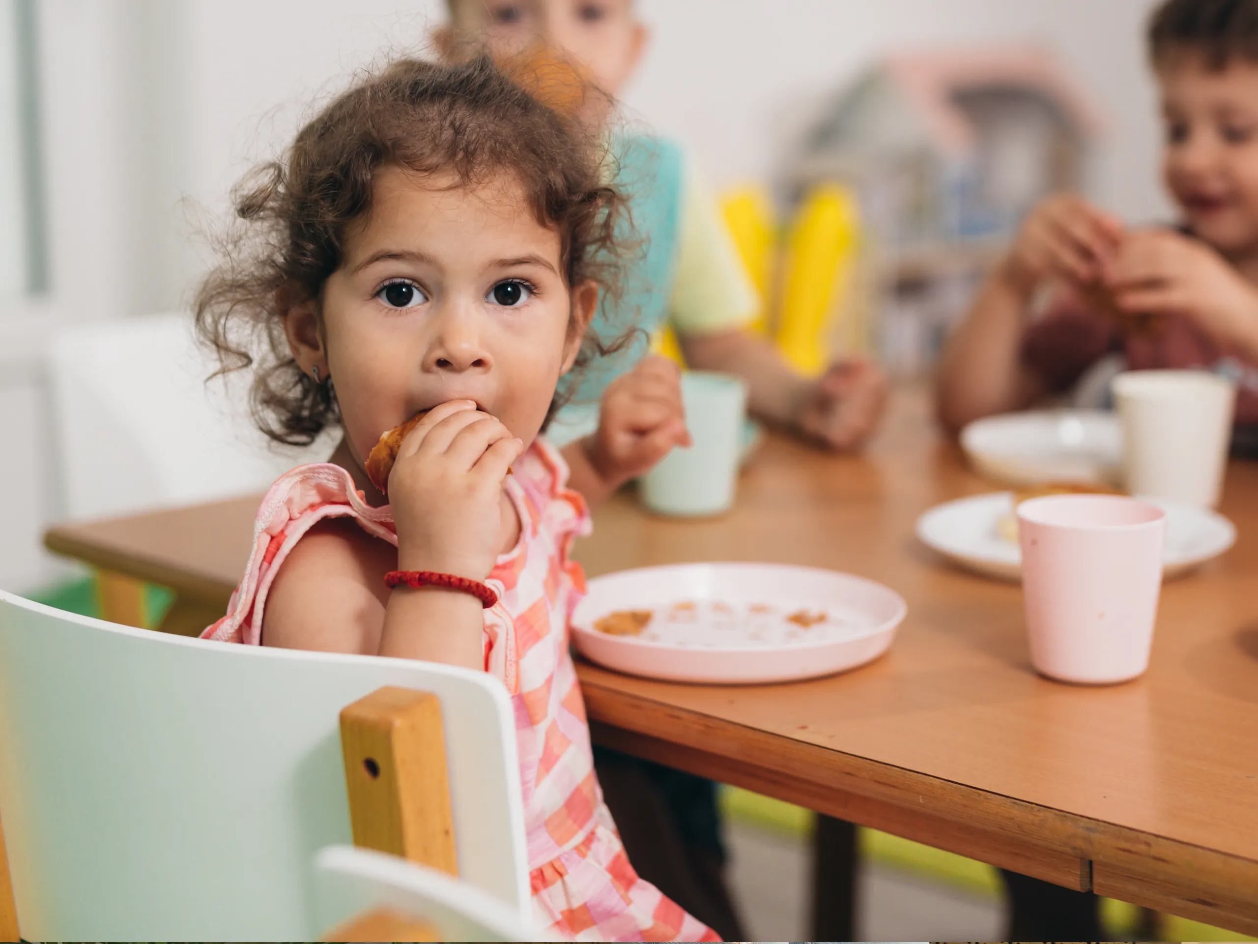 Kid eating at the nursery, looking at the camera