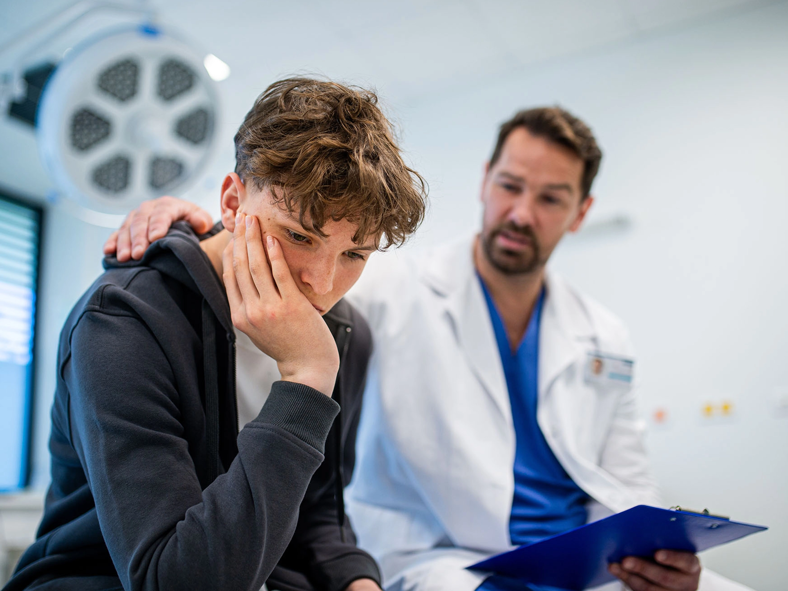 young male being comforted by male doctor