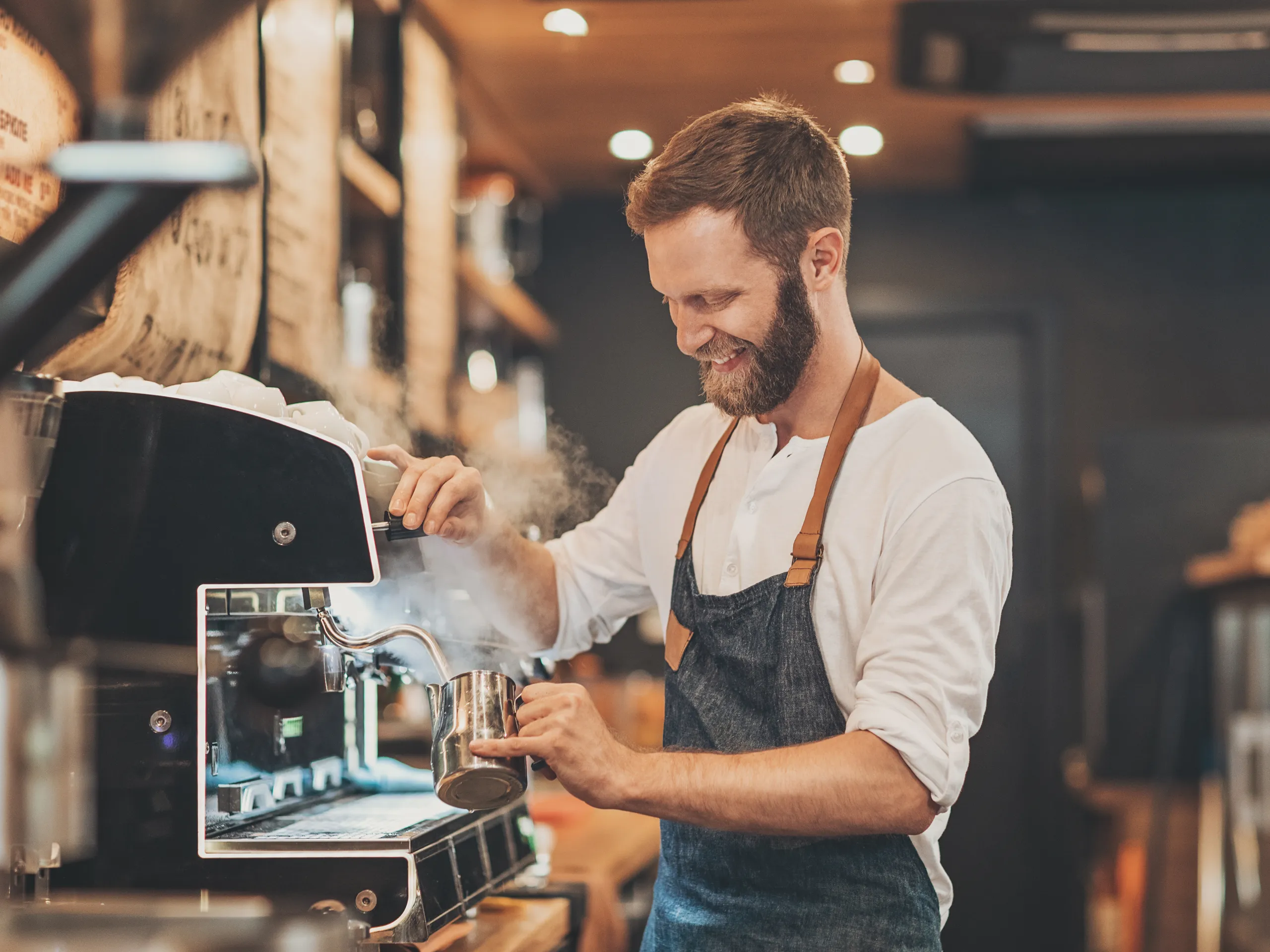 Smiling barista preparing coffee with an espresso machine.
