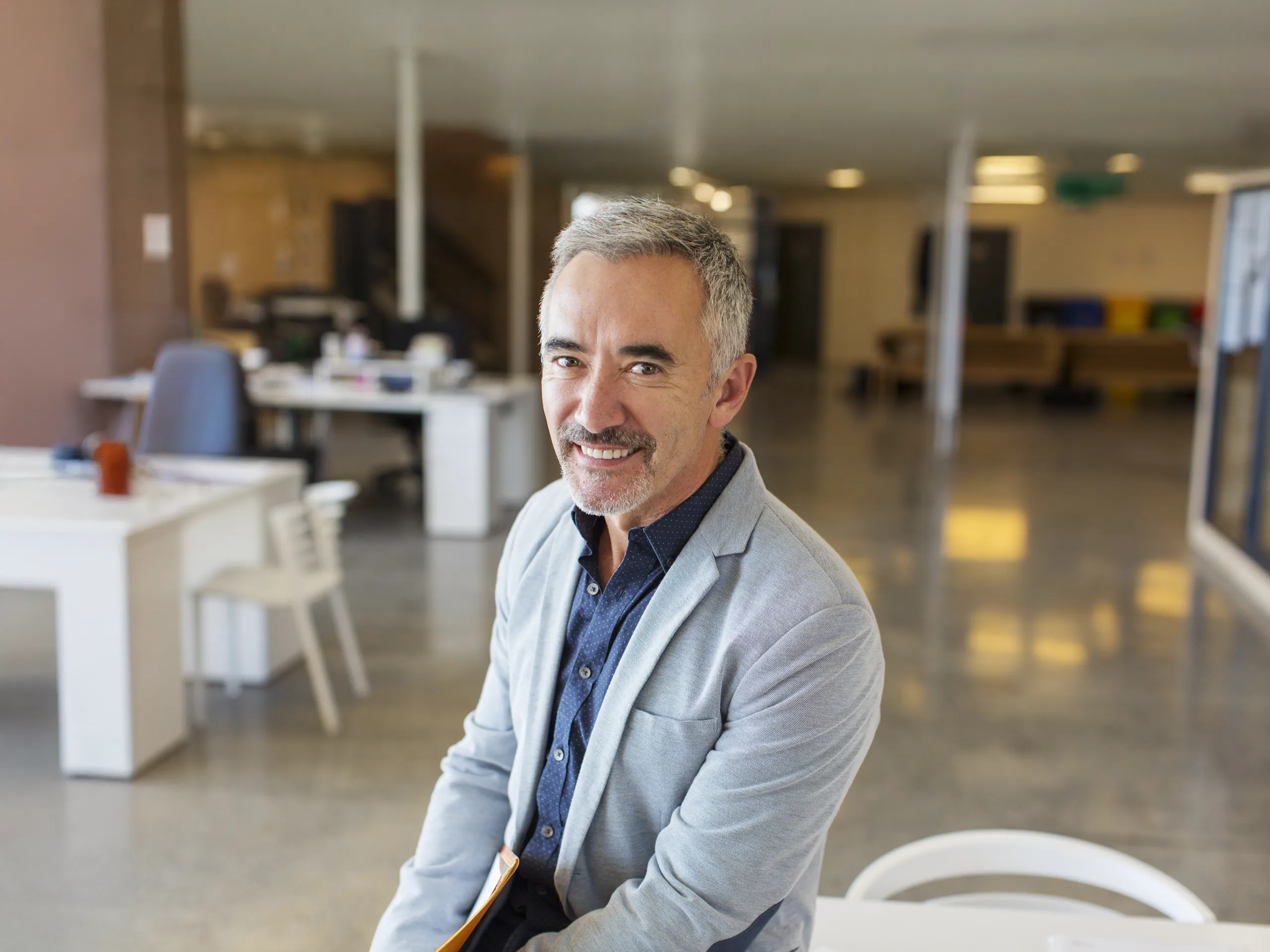 Smiling businessman in a bright open‑plan office.