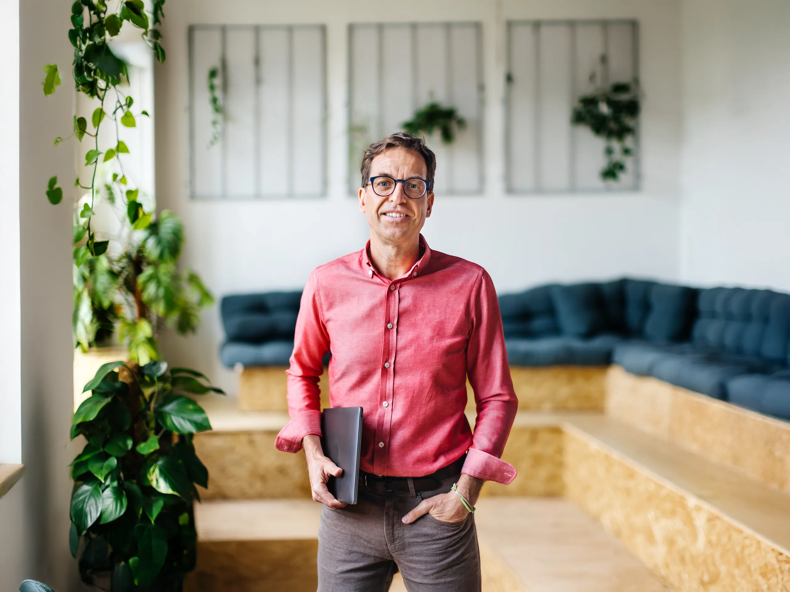 Businessman with tablet standing in a modern office with plants.