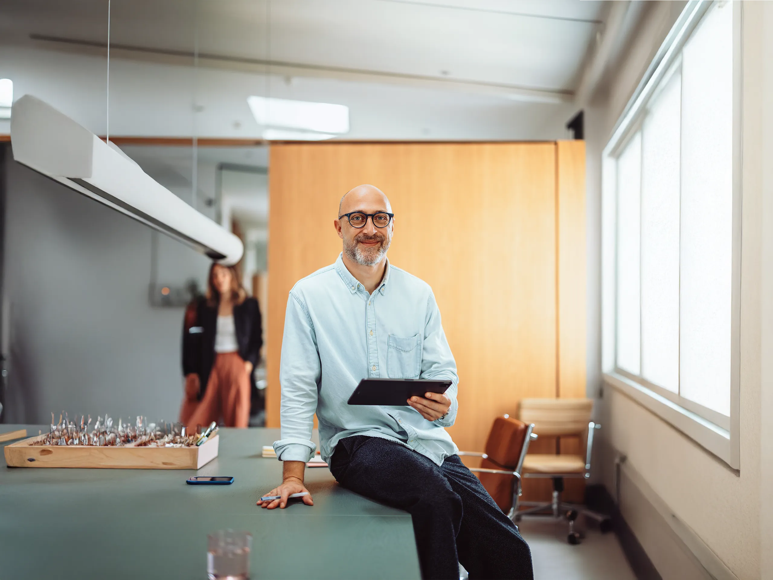 Businessman with tablet sitting casually on a desk in the office.