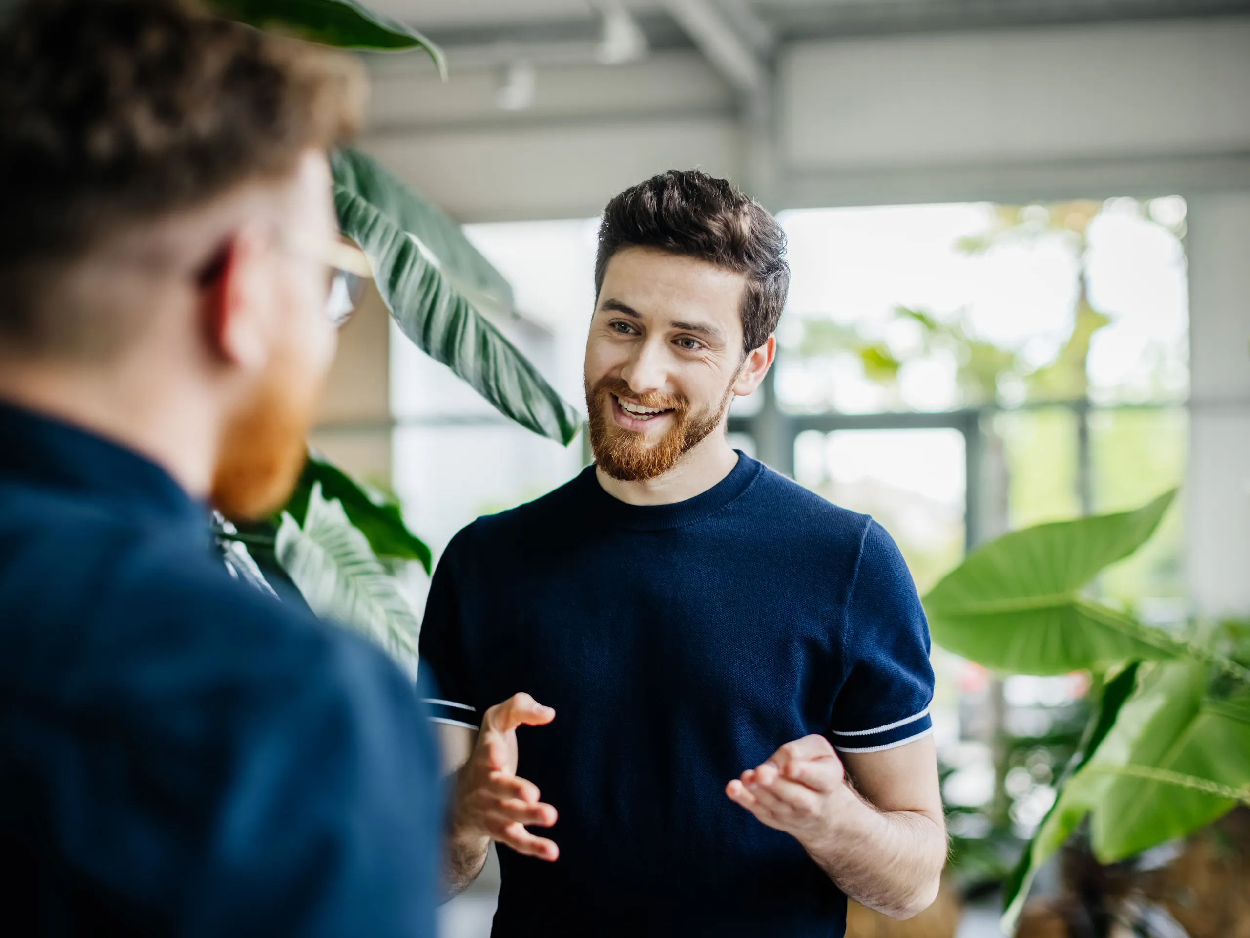 Man talks with another person in a modern office.