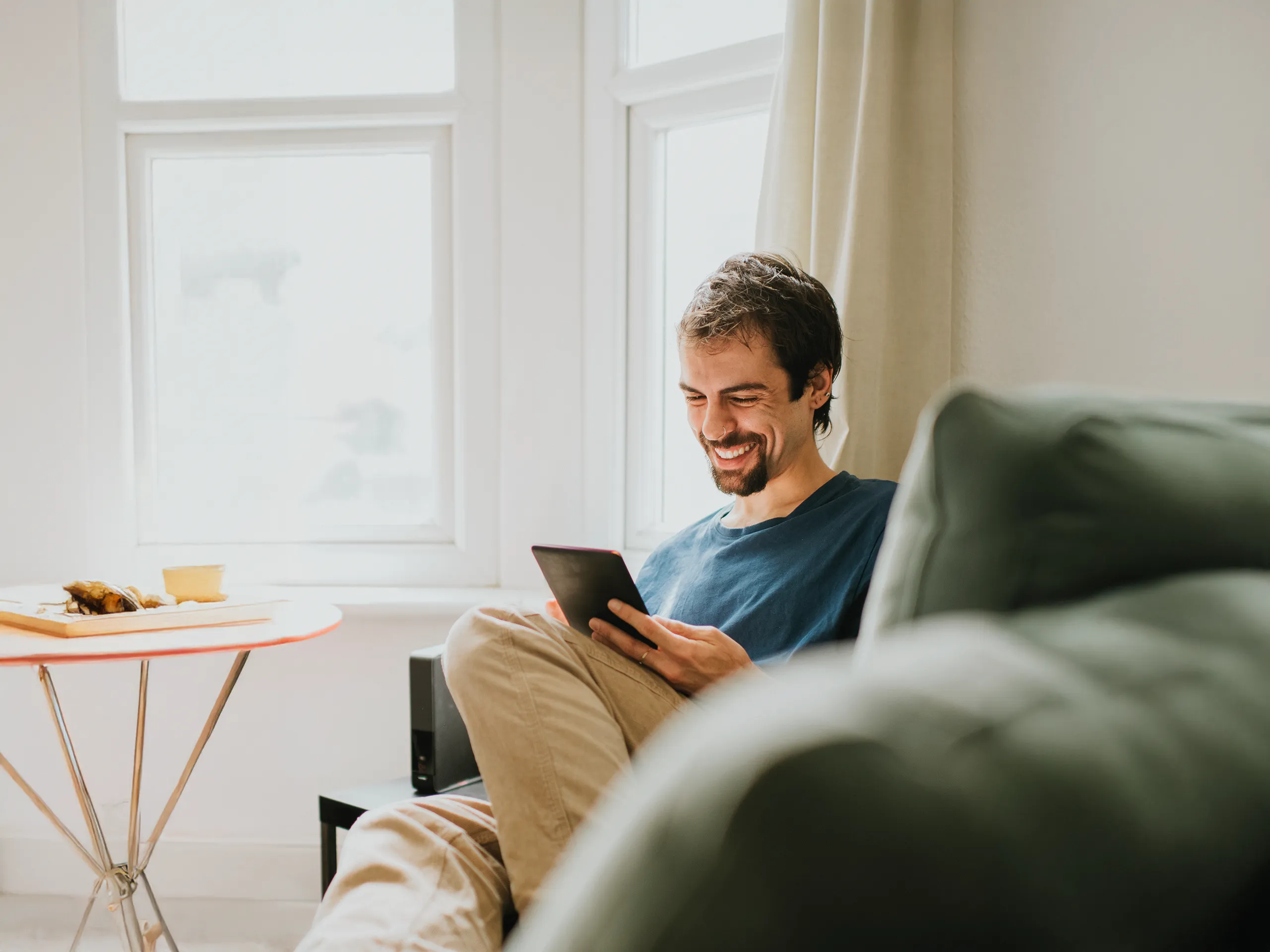 Man reading relaxed on a tablet in the living room.