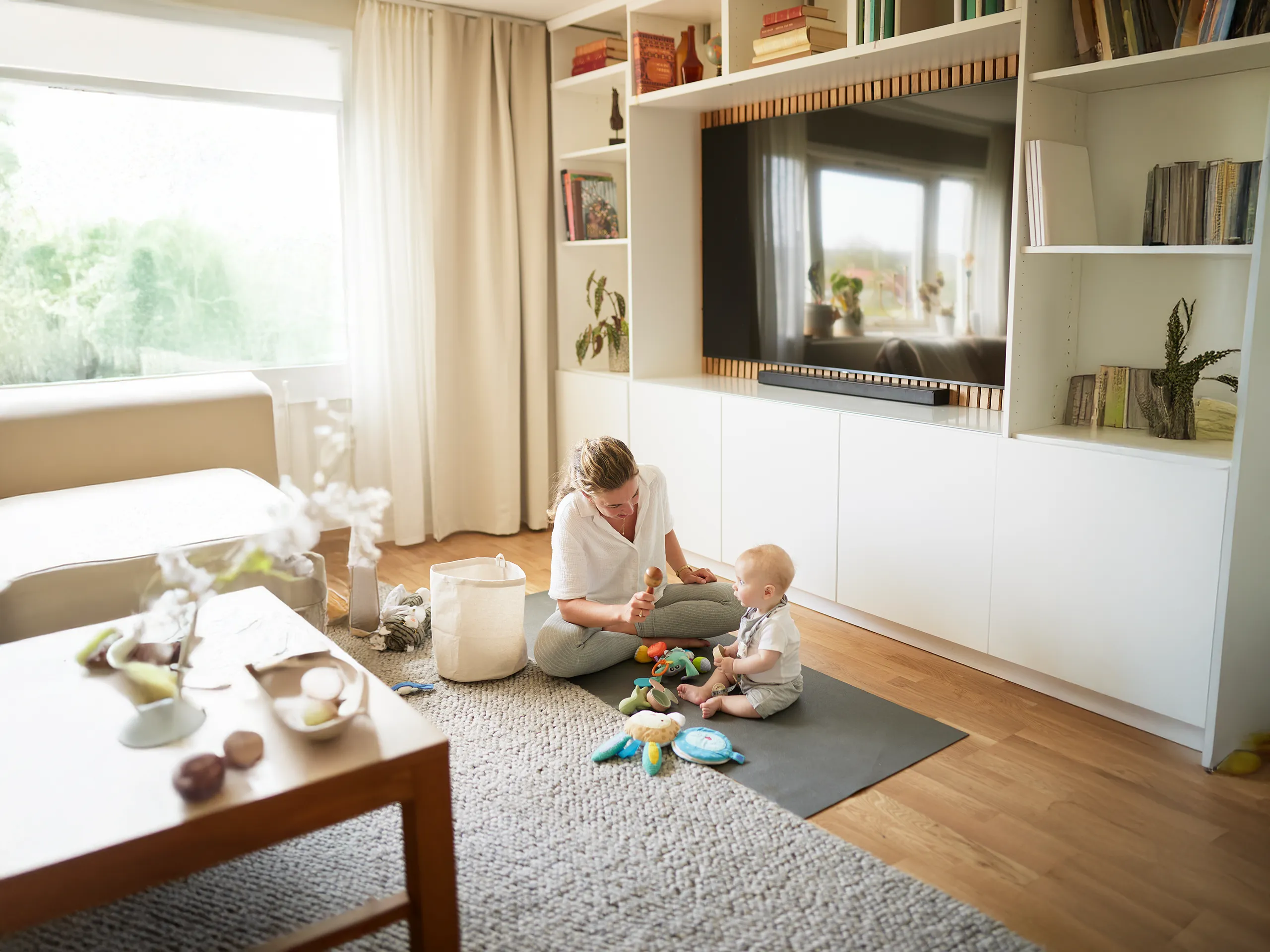 Mother playing with baby on a play mat in the living room.