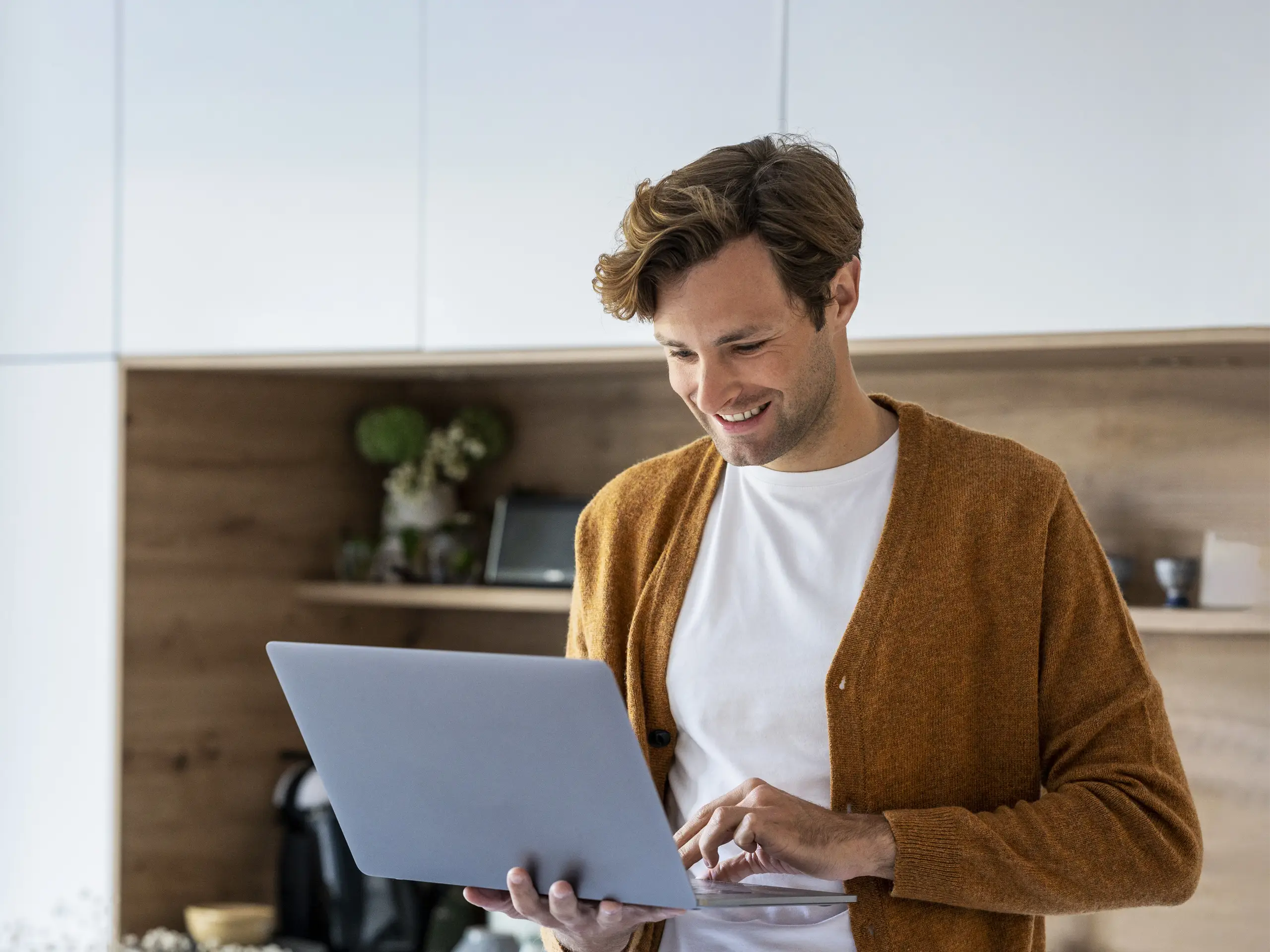 Person standing indoors holding a laptop.