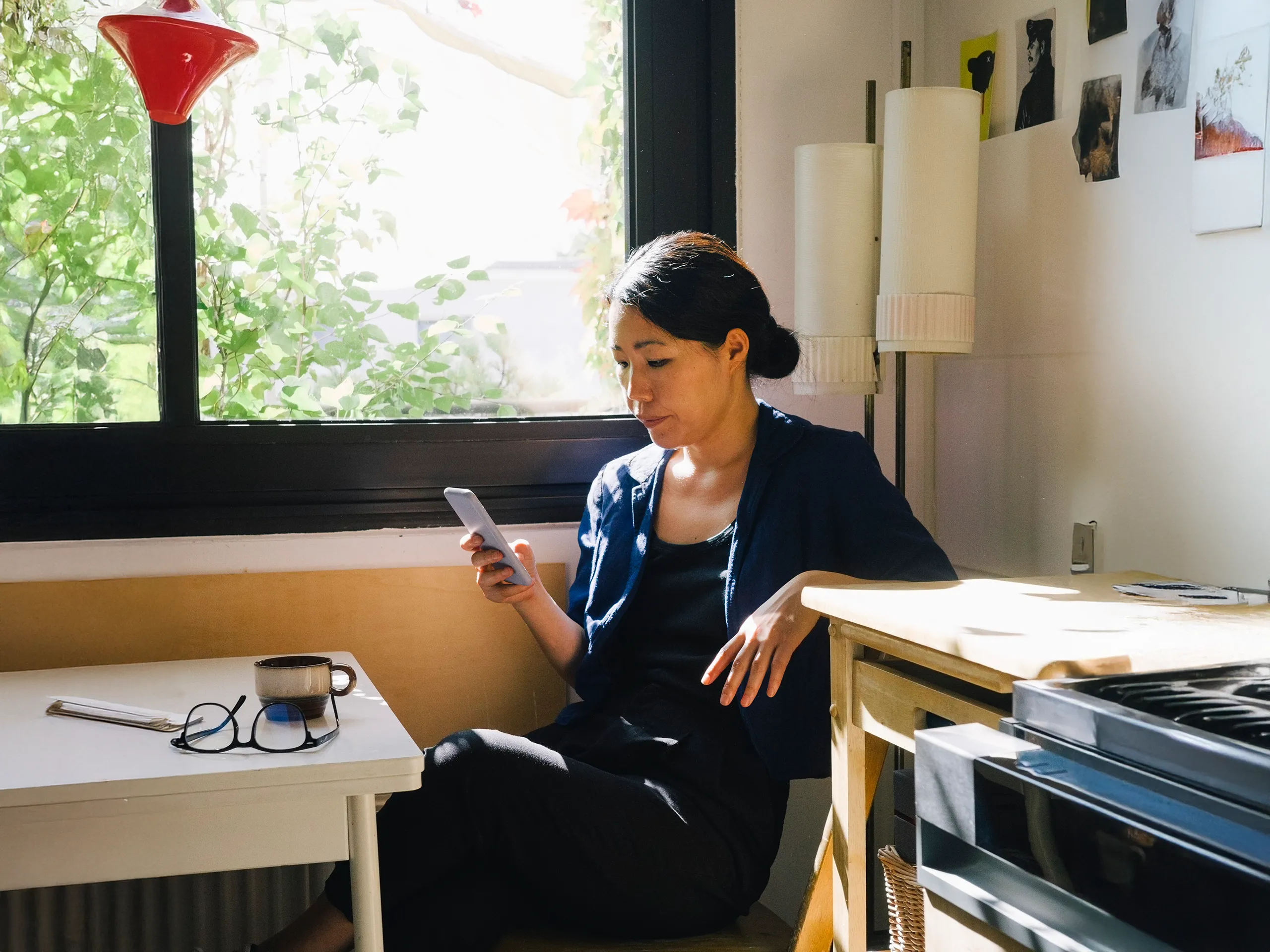 Woman sits relaxed in the sun and looks at her smartphone.