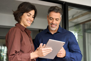 A man and woman look at an ipad in an office