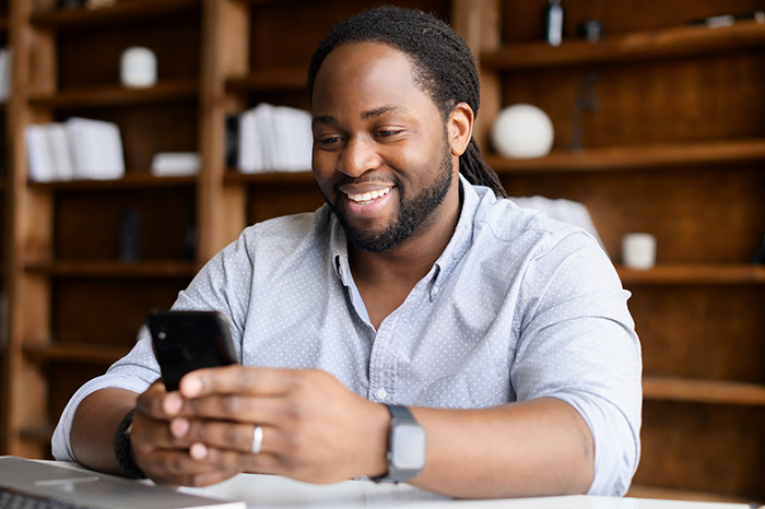 man-phone-helplines-listing Smiling man wearing smart casual shirt is using smartphone