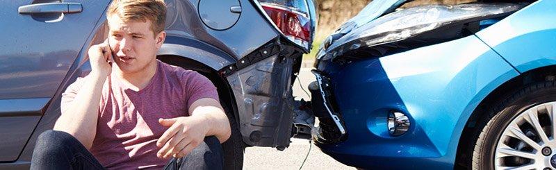 A man sat on the phone against a car