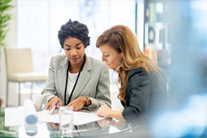 Twoi business women discuss a report at a table in a meeting